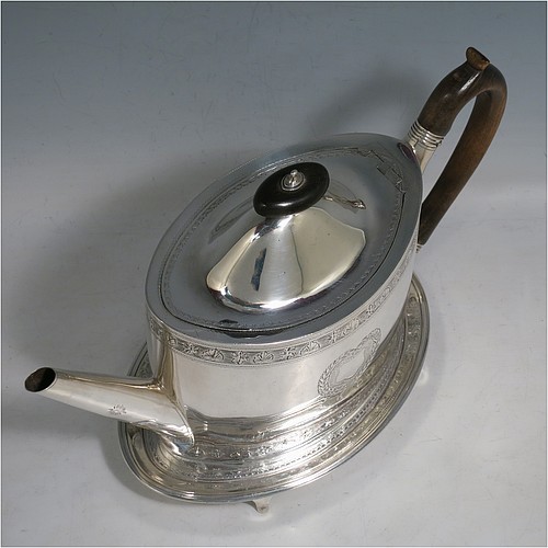 An Antique Georgian Sterling Silver teapot on stand, having a hand-engraved oval body, with bands of floral decoration, a hinged domed lid with wooden finial and flat hidden hinge, a wooden scroll handle, and sitting on a matching stand with four flanged feet and reeded border. The teapot made by Frances Purton of London in 1794, and the stand by Timothy Renou of London in 1795. The dimensions of this fine hand-made antique silver teapot on stand are length 26 cms (10.25 inches), height (on stand) 16 cms (6.25 inches), and it weighs approx. 475g (15.2 troy ounces).    