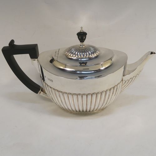 A very handsome Antique Victorian Sterling Silver teapot, having an oval body with hand-chased straight half fluting, a wooden insulated handle, a hinged domed lid with fluting, a wooden finial, and all sitting on a collet foot. This elegant antique silver teapot was made by Edward Hutton of London in 1891. The dimensions of this fine hand-made antique silver teapot are height 15 cms (6 inches), length 27.5 cms (10.75 inches), and it weighs approx. 550g (17.7 troy ounces).   