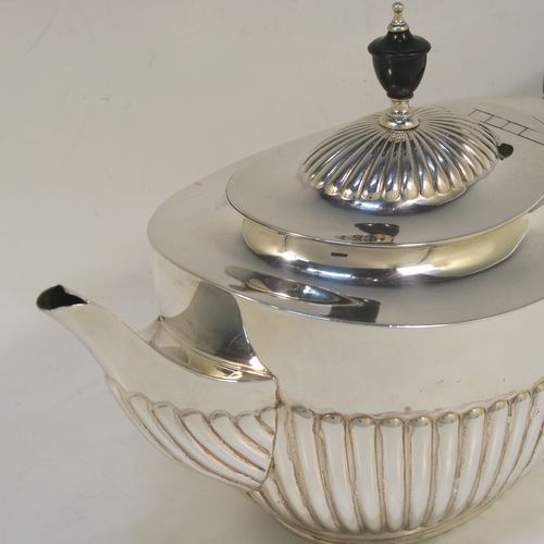 A very handsome Antique Victorian Sterling Silver teapot, having an oval body with hand-chased straight half fluting, a wooden insulated handle, a hinged domed lid with fluting, a wooden finial, and all sitting on a collet foot. This elegant antique silver teapot was made by Edward Hutton of London in 1891. The dimensions of this fine hand-made antique silver teapot are height 15 cms (6 inches), length 27.5 cms (10.75 inches), and it weighs approx. 550g (17.7 troy ounces).   