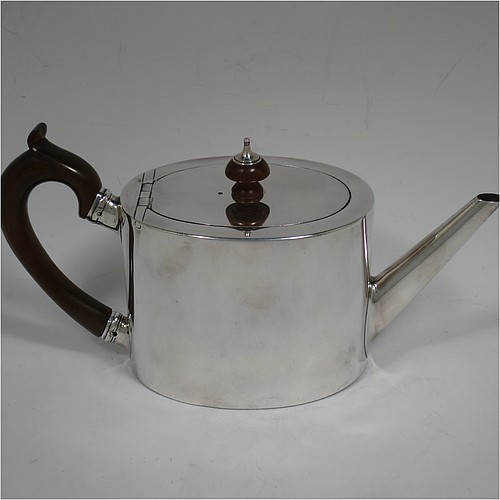 A very handsome Neoclassical style Antique Georgian Sterling Silver teapot in a Bachelor size for two people, having a very plain oval straight-sided body, a straight tapering spout, a wooden scroll handle and round finial, an invisibly hinged flat lid, and all sitting on a flat base. Made by Charles Aldridge and Henry Green of London in 1780. The dimensions of this fine hand-made antique silver bachelor teapot are length 23 cms (9 inches), height 12 cms (4.75 inches), and it weighs approx. 310g (31 troy ounces).    