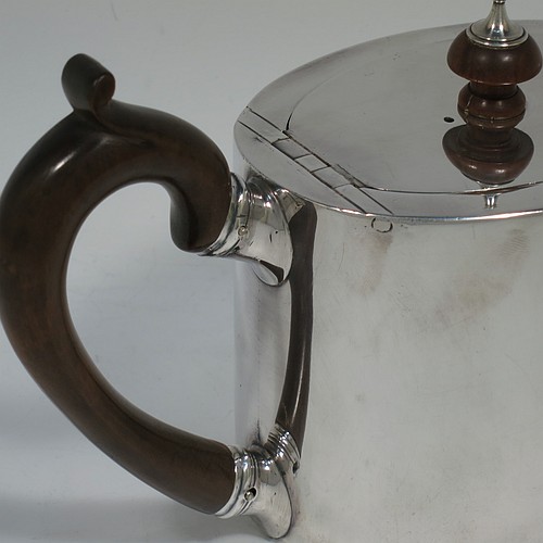 A very handsome Neoclassical style Antique Georgian Sterling Silver teapot in a Bachelor size for two people, having a very plain oval straight-sided body, a straight tapering spout, a wooden scroll handle and round finial, an invisibly hinged flat lid, and all sitting on a flat base. Made by Charles Aldridge and Henry Green of London in 1780. The dimensions of this fine hand-made antique silver bachelor teapot are length 23 cms (9 inches), height 12 cms (4.75 inches), and it weighs approx. 310g (31 troy ounces).    