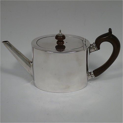 A very handsome Neoclassical style Antique Georgian Sterling Silver teapot in a Bachelor size for two people, having a very plain oval straight-sided body, a straight tapering spout, a wooden scroll handle and round finial, an invisibly hinged flat lid, and all sitting on a flat base. Made by Charles Aldridge and Henry Green of London in 1780. The dimensions of this fine hand-made antique silver bachelor teapot are length 23 cms (9 inches), height 12 cms (4.75 inches), and it weighs approx. 310g (31 troy ounces).    