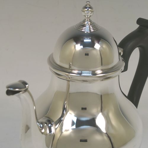 A heavy and very handsome Sterling Silver teapot, in a George I style with a plain round bellied body, having a hinged domed lid with cast finial, a wooden insulated handle, a curved and panelled spout, and all sitting on a round collet foot. This elegant silver teapot was made by Ellis Jacob Greenberg of London in 1928. The dimensions of this fine hand-made heavy silver teapot are height 19 cms (7.5 inches), length 21 cms (8.25 inches), and it weighs approx. 613g (19.8 troy ounces).  