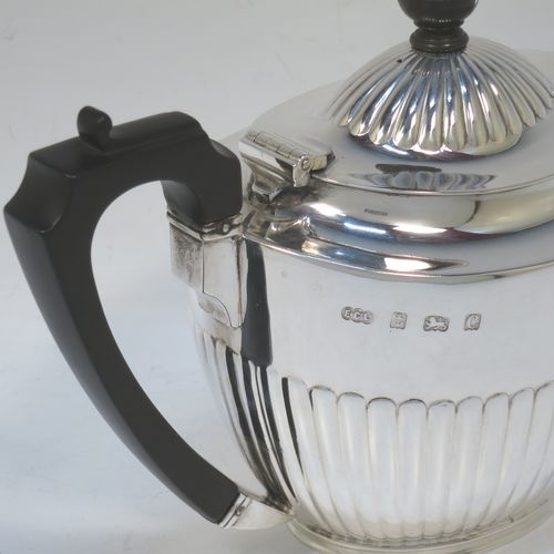 A very handsome Antique Edwardian Sterling Silver teapot, having an oval body with hand-chased straight half fluting, a wooden insulated handle, a hinged domed lid with fluting, a wooden finial, and all sitting on a collet foot. Made by Elkington and Co. Ltd., of Birmingham in 1902. The dimensions of this fine hand-made antique silver teapot are height 14.5 cms (5.75 inches), length 24 cms (9.5 inches), and it weighs is approx. 450g (14.5 troy ounces).   