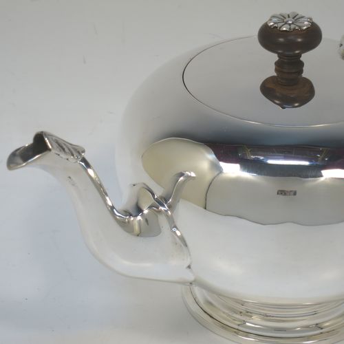 A very handsome Sterling Silver bachelor size teapot in an early George II Bullet or Skittle Ball style, having a plain round bellied body, a curved spout, a wooden scroll handle and finial with silver mount, a hinged lid, and sitting on a pedestal foot. Made by Mappin and Webb of London in 1926. The dimensions of this fine hand-made silver bachelor teapot are length 23 cms (9 inches), height 12 cms (4.75 inches), and it weighs approx. 350g (11.3 troy ounces).   