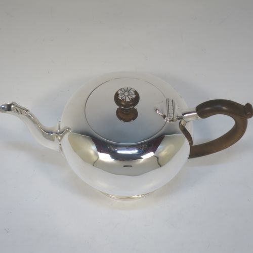 A very handsome Sterling Silver bachelor size teapot in an early George II Bullet or Skittle Ball style, having a plain round bellied body, a curved spout, a wooden scroll handle and finial with silver mount, a hinged lid, and sitting on a pedestal foot. Made by Mappin and Webb of London in 1926. The dimensions of this fine hand-made silver bachelor teapot are length 23 cms (9 inches), height 12 cms (4.75 inches), and it weighs approx. 350g (11.3 troy ounces).   