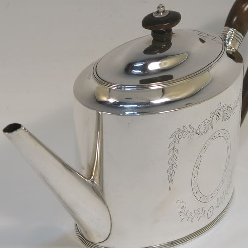 A very handsome Neoclassical style Antique Georgian Sterling Silver teapot, having an oval straight-sided body, with hand-engraved floral swags surrounding vacant cartouches on both sides, a straight tapering spout, a wooden scroll handle and oval finial, an invisibly hinged domed lid, and all sitting on a flat base with a reeded border. This very elegant antique silver teapot was made by Peter and Anne Bateman of London in 1792. The dimensions of this fine hand-made antique silver teapot are length 25.5 cms (10 inches), height 14 cms (5.5 inches), and it weighs approx. 350g (11.3 troy ounces).  