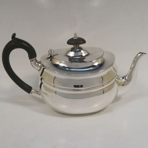 A very handsome Antique Sterling Silver teapot, having a plain oval body with curved sides and reeded decoration, a curved tapering spout, a wooden scroll handle and finial, a hinged domed lid, and all sitting on a flat base. This elegant silver teapot was made by Nathan and Hayes of Chester in 1912. The dimensions of this fine hand-made antique silver teapot are length 23 cms (9 inches), height 12.5 cms (5 inches), and it weighs approx. 350g (11.3 troy ounces).  