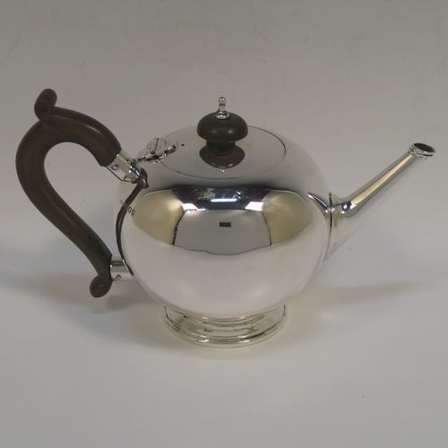 A very handsome Sterling Silver teapot in an early George II Bullet or Skittle Ball style, having a very plain round bellied body, a straight tapering spout, a wooden scroll handle and finial, a hinged flat lid, and sitting on a pedestal foot. This elegant silver teapot was made by Wakely and Wheeler of London in 1936. The dimensions of this fine hand-made silver skittle ball style teapot are length 20 cms (8 inches), height 12 cms (4.75 inches), and it weighs approx. 280g (9 troy ounces).   