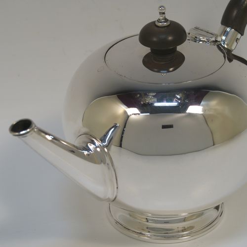 A very handsome Sterling Silver teapot in an early George II Bullet or Skittle Ball style, having a very plain round bellied body, a straight tapering spout, a wooden scroll handle and finial, a hinged flat lid, and sitting on a pedestal foot. This elegant silver teapot was made by Wakely and Wheeler of London in 1936. The dimensions of this fine hand-made silver skittle ball style teapot are length 20 cms (8 inches), height 12 cms (4.75 inches), and it weighs approx. 280g (9 troy ounces).   