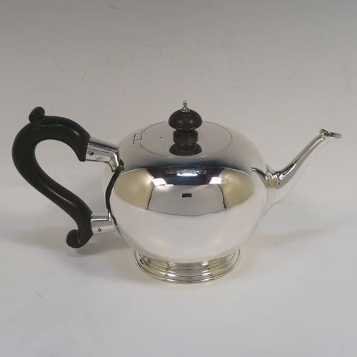 A very handsome Antique Sterling Silver teapot in an early George II Bullet or Skittle Ball style, having a very plain round bellied body, a straight tapering spout, a wooden scroll handle and finial, an invisibly hinged flat lid, and sitting on a pedestal foot. This elegant antique silver teapot was made by Charles Stuart Harris of London in 1919. The dimensions of this fine hand-made silver skittle ball style teapot are length 25.5 cms (10 inches), height 13 cms (5 inches), and it weighs approx. 500g (16 troy ounces).  