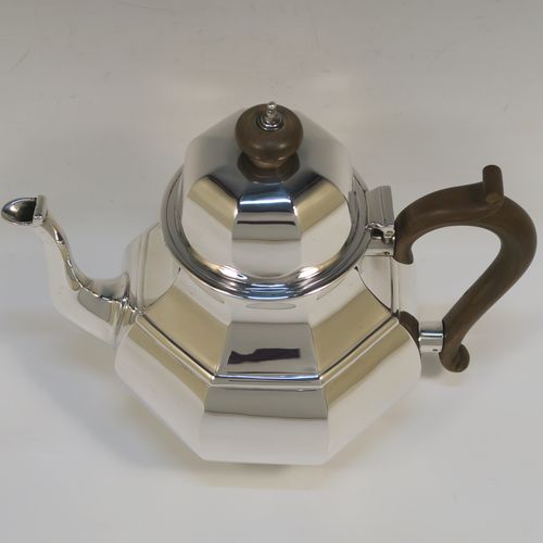 A heavy Antique Sterling Silver George I style large teapot, having a plain panelled bellied body, with a wooden scroll handle, a hinged domed lid with wooden  finial, a panelled spout, and all sitting on a collet foot. This handsome antique silver teapot was made by D. and J. Welby of London in 1918. The dimensions of this fine hand-made silver teapot are height 19 cms (7.5 inches), length 23 cms (9 inches), and the weight is approx. 700g (22.6 troy ounces).   