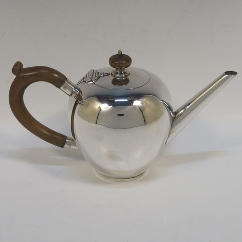 A very handsome Antique Sterling Silver teapot in an early George II Bullet or Skittle Ball style, having a very plain round bellied body, a straight tapering spout, a wooden scroll handle and finial, a hinged flat lid, and sitting on a collet foot. This elegant silver teapot was made by Alexander Osborne London in 1917. The dimensions of this fine hand-made silver skittle ball style teapot are length 23 cms (9 inches), height 12.5 cms 5 inches), and it weighs approx. 340g 11 troy ounces).   