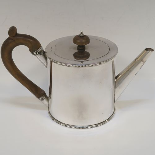 A very handsome Neoclassical style Antique Georgian Sterling Silver Saffron teapot in a very plain round straight-sided body, with applied bead-edged borders, a straight tapering spout, a wooden scroll handle and round finial, an invisibly hinged flat lid, and all sitting on a flat base. This beautiful antique silver saffron teapot was made by Walter Brind of London in 1774. The dimensions of this fine hand-made antique silver teapot are length 22 cms (8.75 inches), height 13.5 cms (5.3 inches), and it weighs approx. 450g (14.5 troy ounces).   