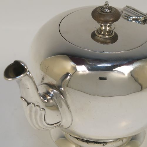 A very handsome Sterling Silver bachelor sized teapot in an early George II Bullet or Skittle Ball style, having a very plain round bellied body, a wooden scroll handle and finial, a hinged lid, and sitting on a pedestal foot. This elegant silver teapot was made by Carrington and Co., of London in 1907. The dimensions of this fine hand-made silver skittle ball style teapot are length 19 cms (7.5 inches), height 10 cms (4 inches), and it weighs approx. 250g (8 troy ounces).   