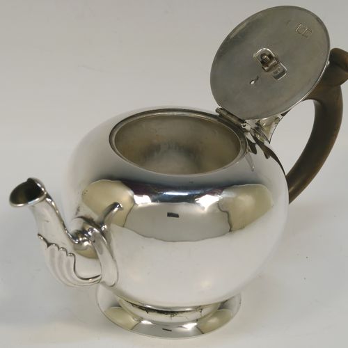 A very handsome Sterling Silver bachelor sized teapot in an early George II Bullet or Skittle Ball style, having a very plain round bellied body, a wooden scroll handle and finial, a hinged lid, and sitting on a pedestal foot. This elegant silver teapot was made by Carrington and Co., of London in 1907. The dimensions of this fine hand-made silver skittle ball style teapot are length 19 cms (7.5 inches), height 10 cms (4 inches), and it weighs approx. 250g (8 troy ounces).   