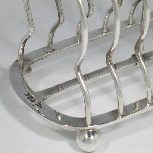 An Antique Victorian Sterling Silver large and heavy seven-bar toast-rack, having plain shaped & rounded wire-work bars, a round handle, sitting on a rectangular base with a strengthening strut, and four ball feet. Made by Walker & Hall of Sheffield in 1898. The dimensions of this fine hand-made antique silver toastrack are length 18 cms (7 inches), height 16.5 cms (6.5 inches), width 9.5 cms (3.75 inches), and it weighs approx. 382g (12.3 troy ounces).   