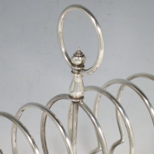 An Antique Victorian Sterling Silver large and heavy seven-bar toast-rack, having plain shaped & rounded wire-work bars, a round handle, sitting on a rectangular base with a strengthening strut, and four ball feet. Made by Walker & Hall of Sheffield in 1898. The dimensions of this fine hand-made antique silver toastrack are length 18 cms (7 inches), height 16.5 cms (6.5 inches), width 9.5 cms (3.75 inches), and it weighs approx. 382g (12.3 troy ounces).   