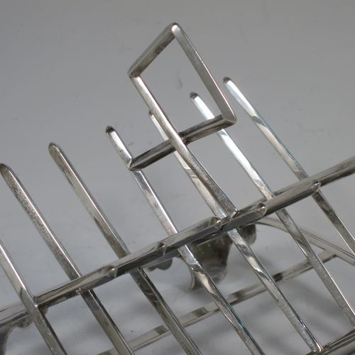 A very unusual Arts and Crafts style Antique Victorian Sterling Silver seven-bar toast-rack, in a very angular style inspired by a Christopher Dresser design, attached to a rectangular base with a reeded border and a strengthening strut, and sitting on four cast foliate and scroll feet. Made by Henry Stratford (who had links with Christopher Dresser) of Sheffield in 1893. The dimensions of this fine hand-made antique silver toast-rack are length 16 cms (6.25 inches), height 14 cms (5.5 inches), width 10 cms (4 inches), and it weighs approx. 348g (11.2 troy ounces).   