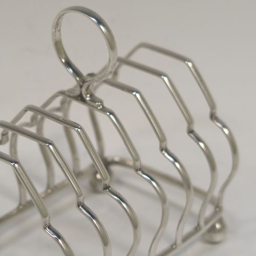 A very elegant Antique Sterling Silver seven-bar toastrack, having plain shaped cross-section wire-work bars, a matching loop handle, and all sitting on a rectangular base with four cast ball feet. This handsome antique silver toast-rack was made by Alexander Clark and Co. Ltd., of Birmingham in 1918. The dimensions of this fine hand-made antique silver toast-rack are length 13 cms (5 inches), height 12 cms (4.75 inches), width 8 cms (3.25 inches), and it weighs approx. 160g (5.2 troy ounces).   