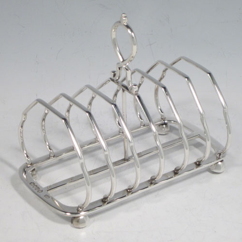 Antique Victorian sterling silver seven-bar toastrack, having shaped wire-work bars, a crossed loop handle, sitting on a rectangular base with a strengthening strut, and four cast octagonal feet. Made by Edward Gilbert of London in 1883. The dimensions of this fine hand-made silver toastrack are length 13.5 cms (5.25 inches), height 11.5 cms (4.5 inches), width 8 cms (3.25 inches), and it weighs approx. 182g (6 troy ounces).