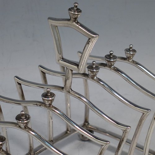 An Antique Victorian Sterling Silver Gothic style large and heavy seven-bar toast-rack, having unusual shaped square wire-work bars all with cast urn-shaped finials, a matching handle, sitting on a curved rectangular base, and four ball feet. Made by Martin & Hall of London in 1883. The dimensions of this fine hand-made antique silver toastrack are length 13.5 cms (5.25 inches), height 13 cms (5 inches), width 8 cms (3.25 inches), and it weighs approx. 222g (7.2 troy ounces).    