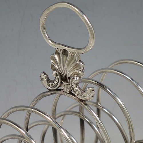 A very large and heavy Antique Georgian Sterling Silver seven-bar toast-rack, having shaped wire-work bars, a cast shell and loop handle, attached to a rectangular base with a strengthening strut, and sitting on four cast shell feet. Made by Robert and Samuel Hennell of London in 1809. The dimensions of this fine hand-made antique silver toast-rack are length 18.5 cms (7.25 inches), height 18.5 cms (7.25 inches), width 14 cms (5.5 inches), and it weighs approx. 550g (17.7 troy ounces).    