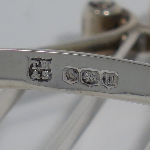 A Sterling Silver seven-bar toastrack or letter rack, having a very unusual Lyre style body with wire-work bars, a loop handle, and sitting on a base with a strengthening strut and four fluted and flanged feet. Made by Thomas Bradbury of Sheffield in 1937. The dimensions of this fine hand-made Lyre-shaped silver letter-rack or toast-rack are length 14 cms (5.5 inches), height 15 cms (6 inches), width 7 cms (2.75 inches), and it weighs approx. 202g (6.5 troy ounces).    