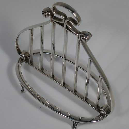 A Sterling Silver seven-bar toastrack or letter rack, having a very unusual Lyre style body with wire-work bars, a loop handle, and sitting on a base with a strengthening strut and four fluted and flanged feet. Made by Thomas Bradbury of Sheffield in 1937. The dimensions of this fine hand-made Lyre-shaped silver letter-rack or toast-rack are length 14 cms (5.5 inches), height 15 cms (6 inches), width 7 cms (2.75 inches), and it weighs approx. 202g (6.5 troy ounces).    