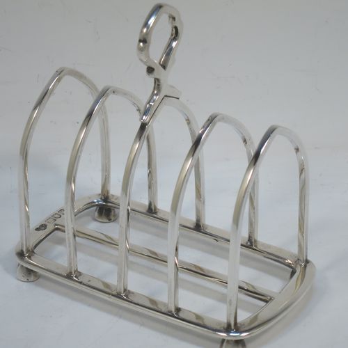 A handsome Antique Sterling Silver five-bar toastrack, having plain square cross-section wire-work bars, a matching loop handle, all sitting on a rectangular base with a strengthening strut, on four cast panelled feet. Made by Goldsmiths & Silversmiths of London in 1912. The dimensions of this fine hand-made antique silver toast-rack are length 11.5 cms (4.5 inches), height 11.5 cms (4.5 inches), width 6.5 cms (2.5 inches), and it weighs approx. 191g (6.2 troy ounces).  