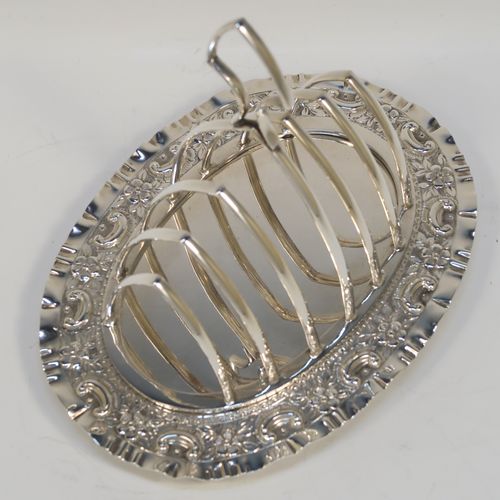 A very pretty Antique Victorian Silver Plated seven-bar toast-rack, having seven arch-shaped and graduated wire-work toast holders, attached to a crumb plate with a hand-chased scroll and floral decorated border, and all sitting on four ball feet. This beautiful antique toastrack was made by Joseph Rogers of Sheffield in ca. 1880. The dimensions of this fine hand-made antique silver-plated toast-rack are length 18 cms (7 inches), height 15 cms (6 inches), and width 13 cms (5 inches).   