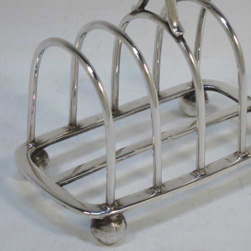 A handsome Sterling Silver five-bar toastrack, having plain rounded wire-work bars, a matching loop handle, all sitting on a rectangular base with a strengthening strut, on four cast ball feet. Made by Thomas Bradbury of Sheffield in 1924. The dimensions of this fine hand-made silver toast-rack are length 11.5 cms (4.5 inches), height 11.5 cms (4.5 inches), width 7 cms (2.75 inches), and it weighs approx. 175g (5.6 troy ounces).  