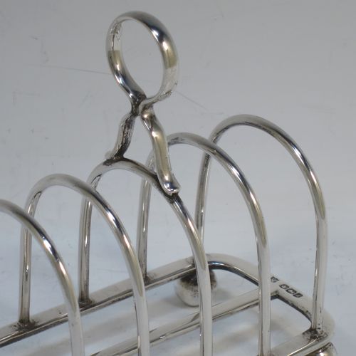 A handsome Sterling Silver five-bar toastrack, having plain rounded wire-work bars, a matching loop handle, all sitting on a rectangular base with a strengthening strut, on four cast ball feet. Made by Thomas Bradbury of Sheffield in 1924. The dimensions of this fine hand-made silver toast-rack are length 11.5 cms (4.5 inches), height 11.5 cms (4.5 inches), width 7 cms (2.75 inches), and it weighs approx. 175g (5.6 troy ounces).  