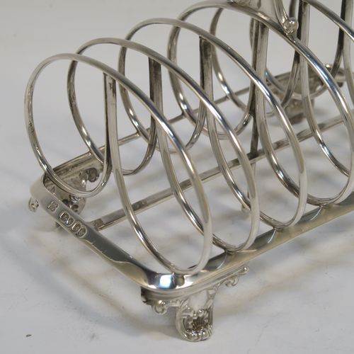 A heavy and elegant Antique Victorian Sterling Silver seven-bar toast-rack, having oval shaped wire-work bars, a cast scroll loop handle, attached to a rectangular base with a strengthening strut, and sitting on four cast shell and scroll feet. This beautiful antique silver toastrack was made by Joseph and John Angell of London in 1841. The dimensions of this fine hand-made antique silver toast-rack are length 16 cms (6.3 inches), height 14 cms (5.5 inches), width 11 cms (4.3 inches), and it weighs approx. 300g (9.7 troy ounces).   