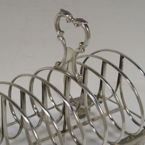 A heavy and elegant Antique Victorian Sterling Silver seven-bar toast-rack, having oval shaped wire-work bars, a cast scroll loop handle, attached to a rectangular base with a strengthening strut, and sitting on four cast shell and scroll feet. This beautiful antique silver toastrack was made by Joseph and John Angell of London in 1841. The dimensions of this fine hand-made antique silver toast-rack are length 16 cms (6.3 inches), height 14 cms (5.5 inches), width 11 cms (4.3 inches), and it weighs approx. 300g (9.7 troy ounces).   