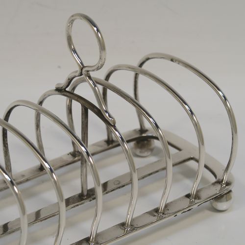 A handsome Antique Sterling Silver seven-bar toastrack, having plain arched cross-section wire-work bars, a loop handle, and all sitting on a rectangular base with a strengthening strut, on four cast ball feet. This elegant antique silver toast-rack was made by Charles Stuart Harris of London in 1911. The dimensions of this fine hand-made antique silver toast-rack are length 13.5 cms (5.3 inches), height 10 cms (4 inches), width 7 cms (2.75 inches), and it weighs approx. 163g (5.3 troy ounces).   