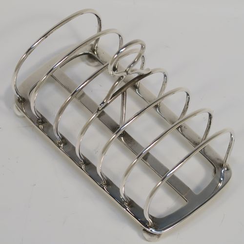 A handsome Antique Sterling Silver seven-bar toastrack, having plain arched cross-section wire-work bars, a loop handle, and all sitting on a rectangular base with a strengthening strut, on four cast ball feet. This elegant antique silver toast-rack was made by Charles Stuart Harris of London in 1911. The dimensions of this fine hand-made antique silver toast-rack are length 13.5 cms (5.3 inches), height 10 cms (4 inches), width 7 cms (2.75 inches), and it weighs approx. 163g (5.3 troy ounces).   