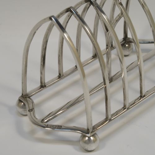 A large and very handsome Antique Edwardian Sterling Silver seven-bar toastrack, having plain arched cross-section wire-work bars, a matching  loop handle, all sitting on a rectangular base with a strengthening strut, on four ball feet. This elegant antique silver toast-rack was made by William Hutton and Sons of London in 1902. The dimensions of this fine hand-made antique silver toast-rack are length 18 cms (7 inches), height 15 cms (6 inches), width 9 cms (3.5 inches), and it weighs approx. 297g (9.6 troy ounces).  