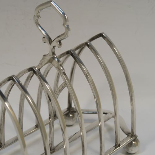 A large and very handsome Antique Edwardian Sterling Silver seven-bar toastrack, having plain arched cross-section wire-work bars, a matching  loop handle, all sitting on a rectangular base with a strengthening strut, on four ball feet. This elegant antique silver toast-rack was made by William Hutton and Sons of London in 1902. The dimensions of this fine hand-made antique silver toast-rack are length 18 cms (7 inches), height 15 cms (6 inches), width 9 cms (3.5 inches), and it weighs approx. 297g (9.6 troy ounces).  