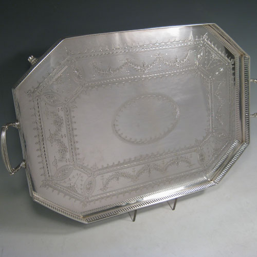 Antique Victorian silver plated tray, having an octagonal sided body, a hand-engraved ground with geometrical and floral swag decoration, a hand-pierced gallery edge, two cast reeded handles, and sitting on four cast reeded flange feet. This beautiful silver-plated tray was made by Latham and Morton in ca. 1880. The dimensions of this fine hand-made silver plated tea tray are length (inc. handles) 53 cms (21 inches), width 33 cms (13 inches).   