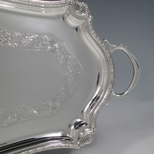 Sterling Silver Sandwich Tray, having a long shaped rectangular body, with hand-engraved ground showing a band of floral decoration, an applied floral border with shell corners, and two cast side-handles, all sitting on a flat base. This very pretty sterling silver sandwich tray was made by Mappin and Webb of Sheffield in 1929. The dimensions of this fine hand-made silver sandwich tray are length (inc. handles) 59 cms (23.25 inches), width 24 cms (9.5 inches), and it weighs approx. 1,361g (44 troy ounces).