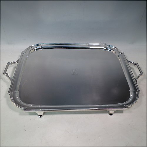 An Antique Edwardian heavy Sterling Silver Georgian style tea tray, having a rectangular body with rounded cut corners, a very plain ground with a centrally engraved crest, an applied reeded border, two cast scroll side-handles, and sitting on four cast flanged feet. Made by Thomas Bradbury of London in 1905. The dimensions of this fine hand-made antique silver tray are length (inc. handles) 53 cms (20.75 inches), width 35 cms (13.75 inches), and it weighs approx. 2,325g (75 troy ounces). Please note that this item is crested.