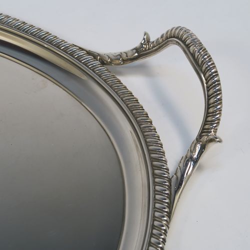 A very elegant Antique Georgian Sterling Silver tray, having an oval body with a plain central ground which is engraved with a part crest, with an applied gadroon border, and two cast gadroon and anthemion leaf side-handles, all sitting on a flat base. This beautiful antique silver tray was made by Crouch and Hannam of London in 1796. The dimensions of this fine hand-made antique silver tray are length (inc. handles) 62 cms (24.5 inches), width 40.5 cms (16 inches), and it weighs approx. 2,460g (79 troy ounces).   