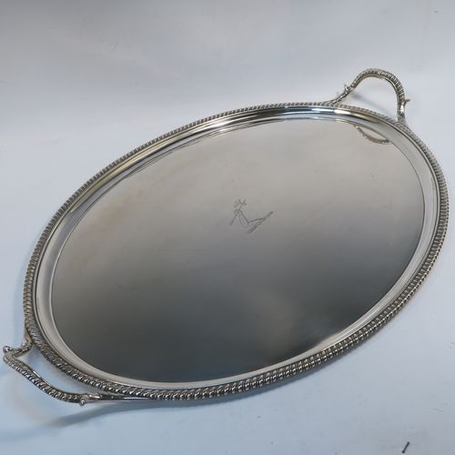 A very elegant Antique Georgian Sterling Silver tray, having an oval body with a plain central ground which is engraved with a part crest, with an applied gadroon border, and two cast gadroon and anthemion leaf side-handles, all sitting on a flat base. This beautiful antique silver tray was made by Crouch and Hannam of London in 1796. The dimensions of this fine hand-made antique silver tray are length (inc. handles) 62 cms (24.5 inches), width 40.5 cms (16 inches), and it weighs approx. 2,460g (79 troy ounces).   