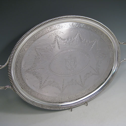 Antique Georgian sterling silver oval two-handled tea tray with beautifully hand-engraved floral and swag decoration, and cast gadroon border. This handsome sterling silver tray was made by William Bennett of London in 1805. The dimensions of this fine hand-made silver tray are length inc. handles 53 cms (21 inches), width 33 cms (13 inches), and it weighs approx. 1,550g (50 troy ounces). Please note that this item is crested in the central cartouche.