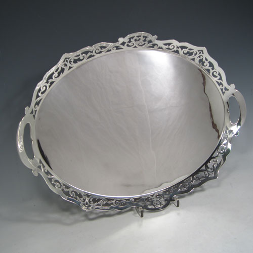 Sterling silver tea tray, having an oval body with a very plain ground, a raised gallery border with hand-pierced scroll decoration, two integral side-handles, and sitting on a flat base. Made by J. Gloster Ltd., of Birmingham in 1932. The dimensions of this fine hand-made silver tray are length (inc. handles) 50 cms (19.75 inches), width 35.5 cms (14 inches), and it weighs approx. 1,300g (42 troy ounces).