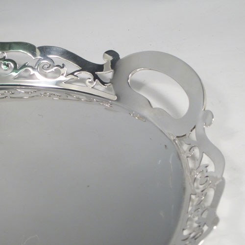 Sterling silver tea tray, having an oval body with a very plain ground, a raised gallery border with hand-pierced scroll decoration, two integral side-handles, and sitting on a flat base. Made by J. Gloster Ltd., of Birmingham in 1932. The dimensions of this fine hand-made silver tray are length (inc. handles) 50 cms (19.75 inches), width 35.5 cms (14 inches), and it weighs approx. 1,300g (42 troy ounces).