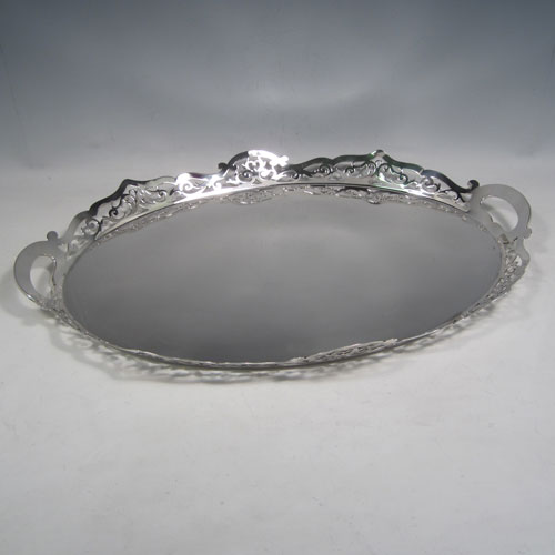 Sterling silver tea tray, having an oval body with a very plain ground, a raised gallery border with hand-pierced scroll decoration, two integral side-handles, and sitting on a flat base. Made by J. Gloster Ltd., of Birmingham in 1932. The dimensions of this fine hand-made silver tray are length (inc. handles) 50 cms (19.75 inches), width 35.5 cms (14 inches), and it weighs approx. 1,300g (42 troy ounces).