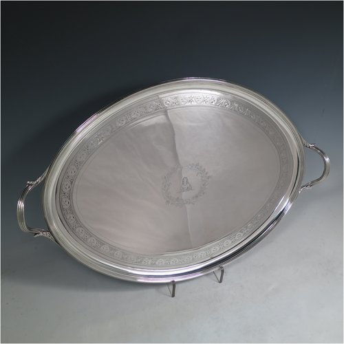 An Antique Georgian Sterling silver oval two-handled tea tray, with a beautifully hand-engraved band of floral decoration, an applied reeded border with matching cast handles, and sitting on a flat base. This handsome Georgian sterling silver tray was made by Elizabeth Jones of London in 1794. The dimensions of this fine hand-made silver tray are length inc. handles 52 cms (20.5 inches), width 34 cms (13.5 inches), and it weighs approx. 1,593g (51 troy ounces).   