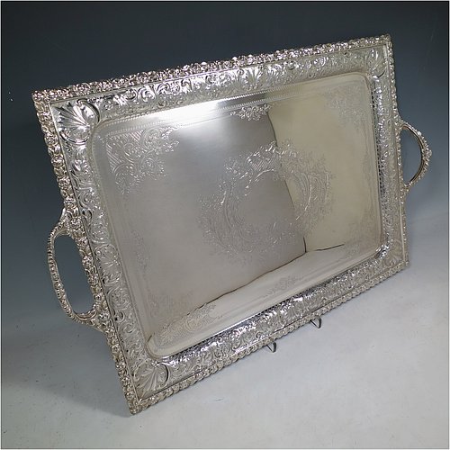 A very pretty Antique Victorian Silver Plated tray, having a rectangular body, a beautiful hand-engraved ground with floral decoration surrounding a central vacant cartouche, a hand-chased border with floral and scroll decoration, with two cast gadroon side-handles, and sitting on a flat base. This beautiful silver-plated tray was made by the Mappin Brothers of Sheffield in their top-quality Queens Plate. The dimensions of this fine hand-made silver plated tea tray are length (inc. handles) 58 cms (22.75 inches), width 38 cms (15 inches).    